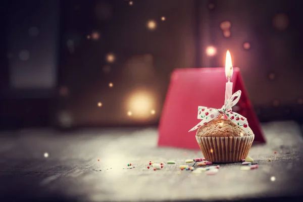 close-up view of cupcake with candle and colorful decoration on wooden background