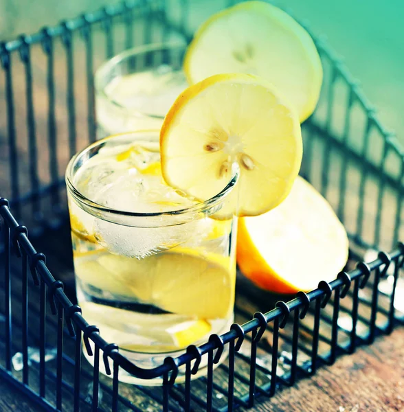 two glasses with lemonade in black iron basket on wooden table