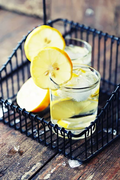 two glasses with lemonade in black iron basket on wooden table