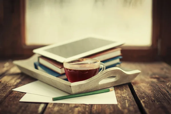Still life with books, digital tablet and cup of hot tea
