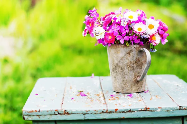 五颜六色的新鲜野花在金属壶在乡村木凳户外的花束 — 图库照片