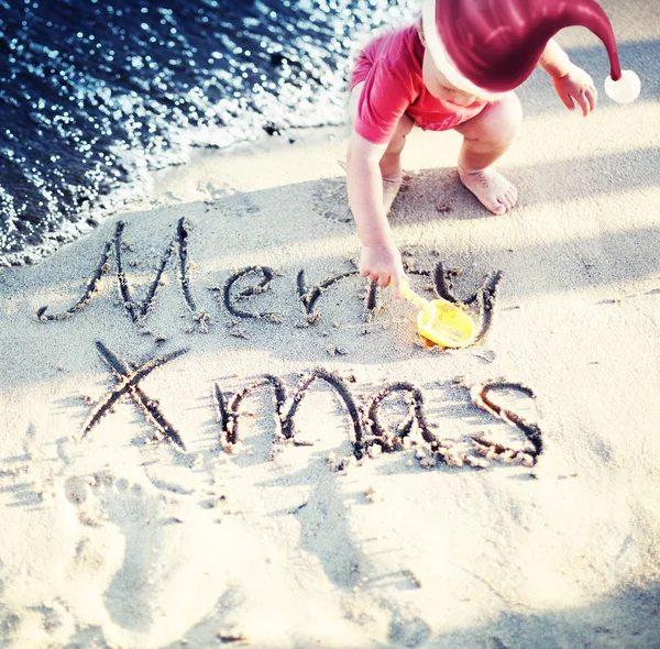 在圣诞老人帽子的男婴画在潮湿的沙滩上的圣诞节 — 图库照片