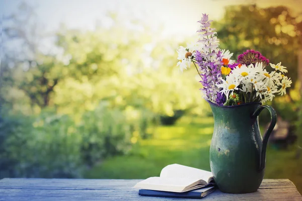 素朴な水差し本の屋外木製テーブルの上にカラフルな新鮮な野生の花の花束 — ストック写真