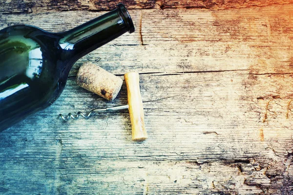 Wine bottle, cork and corkscrew on wooden background