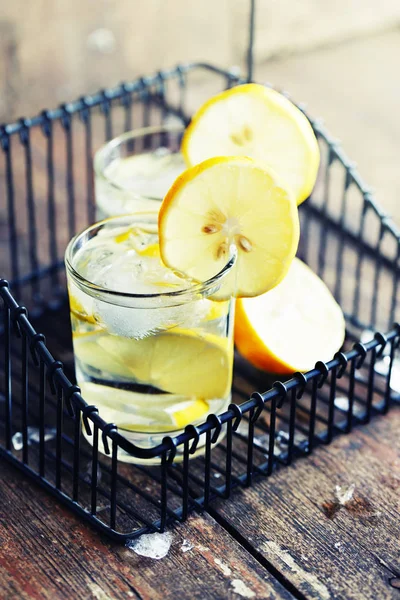 two glasses with lemonade in black iron basket on wooden table