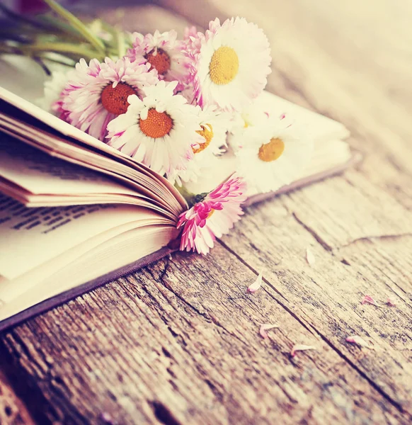 bouquet of rustic flowers on wooden table with open book