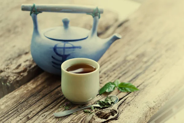 closeup view of fresh tea cup with blue teapot over wooden table