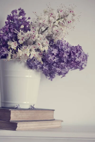 pink and white lilac flowers in bucket on old books