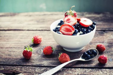 İştah açıcı yaban mersini ve ahşap masa kaşık beyaz kase çilek