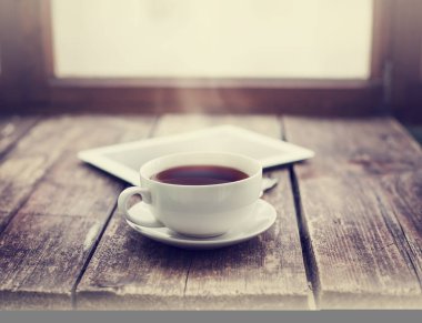 fincan sıcak çay ve dijital tablet ahşap yüzey üzerinde