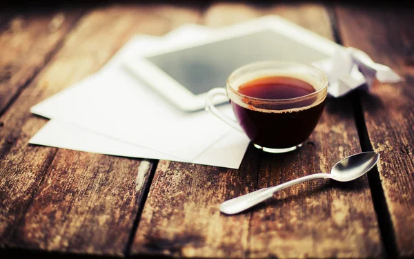 cup of hot tea and digital tablet on wooden surface