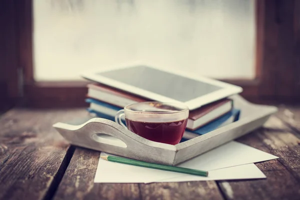closeup view of tea cup and digital tablet lying on wooden table