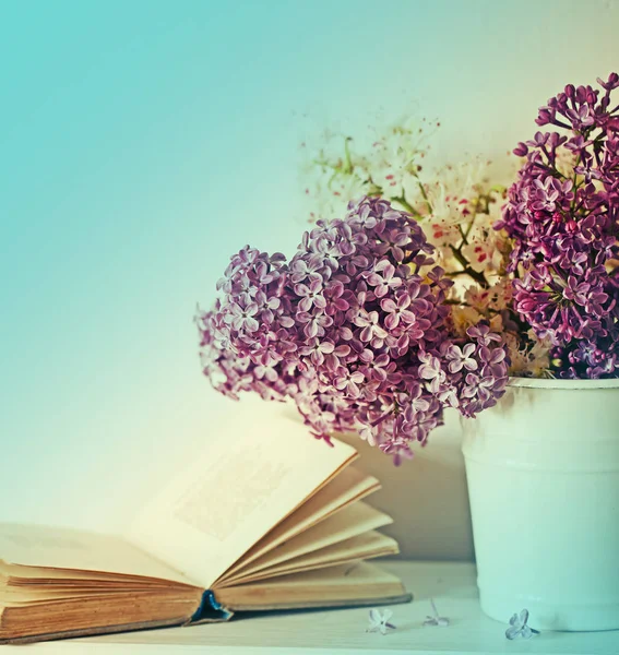 bouquet of purple lilac in vase and old book