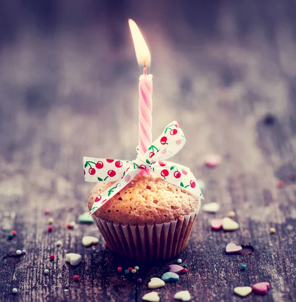 close-up view of cupcake with candle and colorful decoration on wooden background