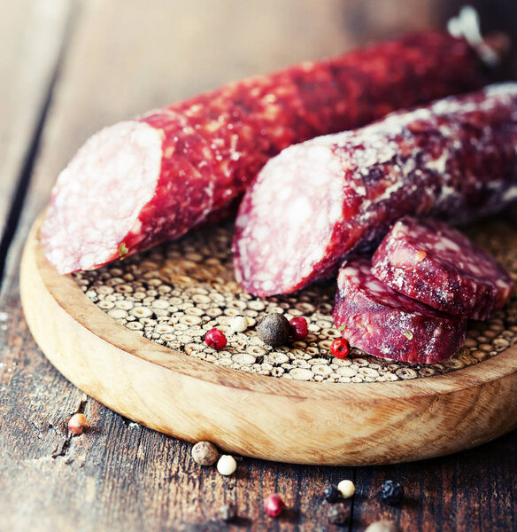 Appetizing sausages on wooden chalkboard with spices
