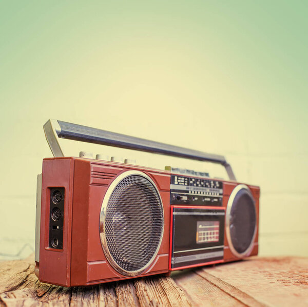 Retro radio player with buttons and antenna on white wall background