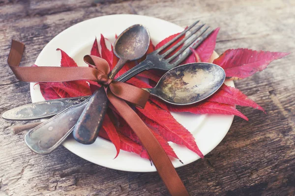 秋の紅葉と木製のテーブルの上の食器プレートのクローズ アップ ビュー — ストック写真