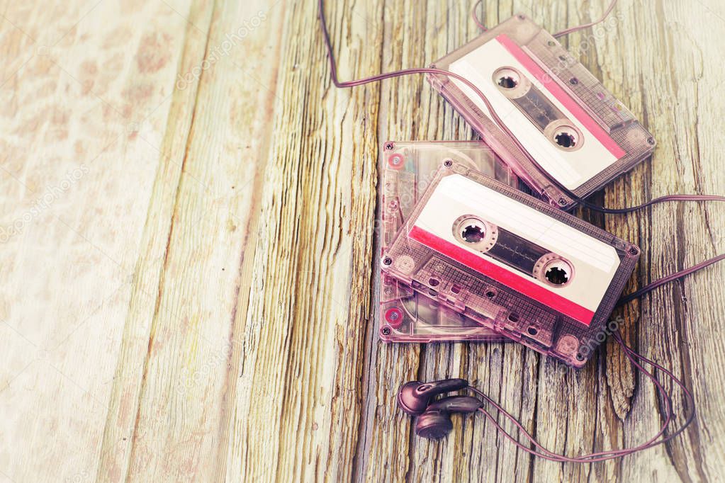 Colorful cassettes with headphones on wooden background
