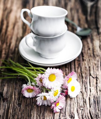 Su bardağı kaşık ve çiçeklerle ahşap arka plan üzerinde yığılmış