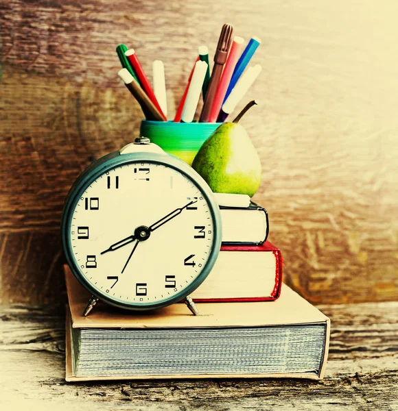 Alarm clock, book stack and felt pens. Back to school concept.