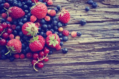 taze çilek, yaban mersini ve yığın ahşap yüzey üzerinde kırmızı kuş üzümü