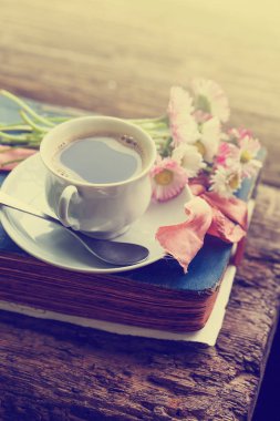 Lezzetli fincan kahve ve Kitaplar, ahşap arka plan üzerinde çiçekler