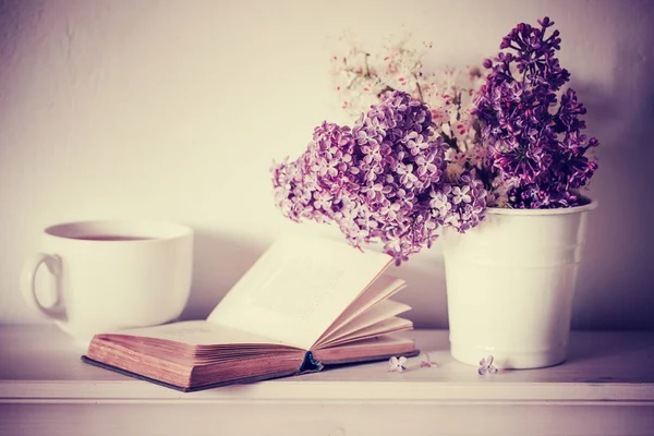 purple lilac with open book and white cup with tea