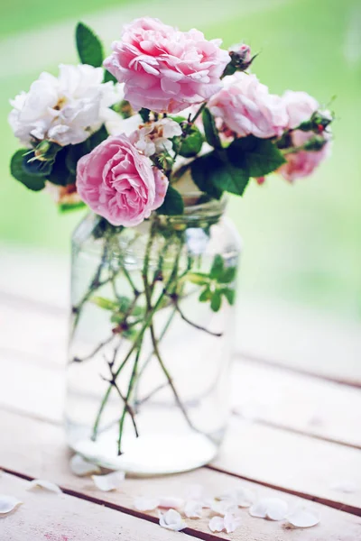 pink and white peony roses in vase on garden wooden table
