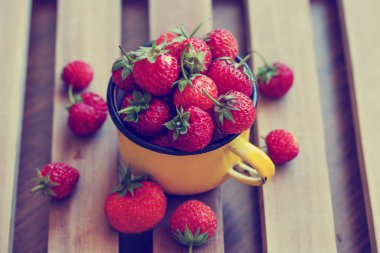 ahşap masa üzerinde taze olgun çilek sarı kupa