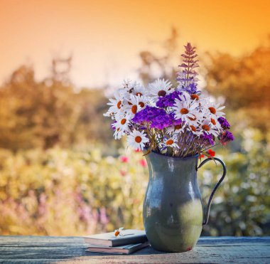 yabani çiçek vazo ayakta bulanık doğa arka plan ile ahşap masa üzerinde
