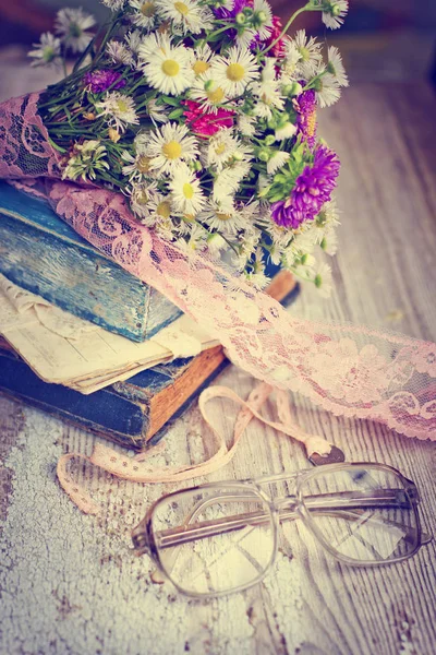 ビンテージの本のぼろぼろの木製テーブルの上の野生の花の花束 — ストック写真