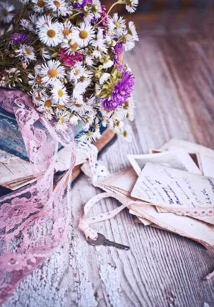 ヴィンテージ本やカードのぼろぼろの木製テーブルの上の野生の花の花束 — ストック写真