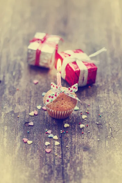 closeup view of cupcake with candle and colorful christmas decorations in vintage style over wooden background