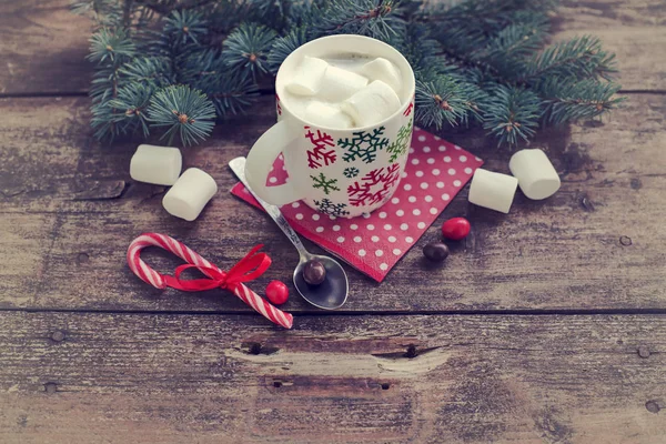 closeup view of coffee cup with marshmallows and christmas decorations over wooden table