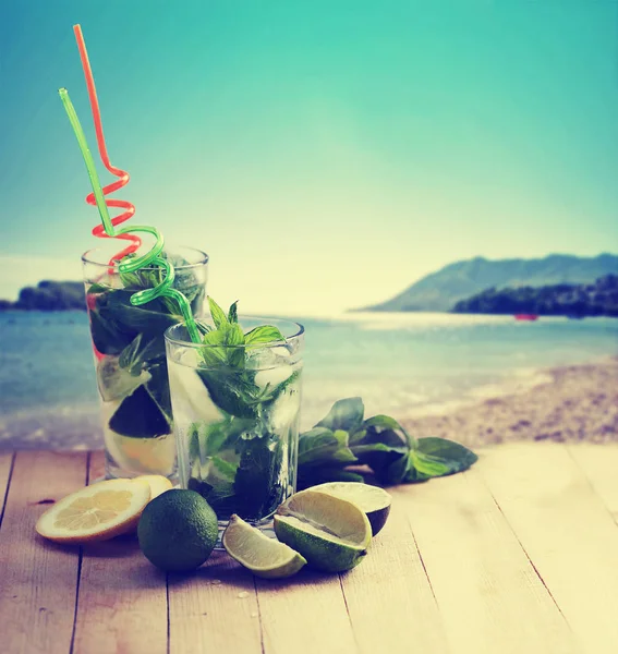 鸡尾酒与稻草在木桌上的背景海滩 — 图库照片