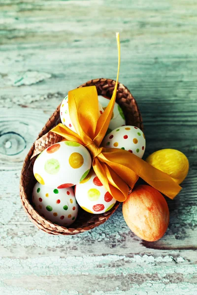 彩色彩绘复活节彩蛋与丝带在篮子在木桌上 — 图库照片