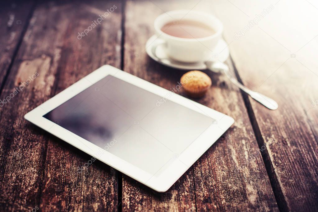 closeup view of coffee cup with digital tablet lying on wooden table