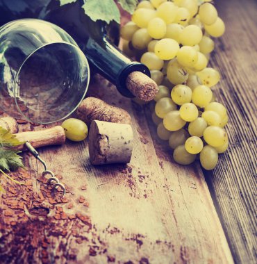 Bir şişe şarap, üzüm ve ahşap masa tarihinde mantarlar