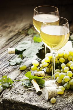 Şişe beyaz şarap gözlük, üzüm ve ahşap masa tarihinde mantarlar