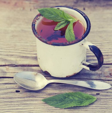 Yeşil yaprakları ve ahşap zemin üzerine kaşık çay