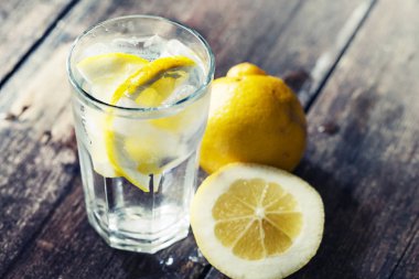 Limonata limon dilimleri buz üzerinde ahşap masa ile bir bardak