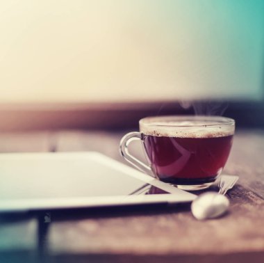 closeup görünümü dijital tablet ahşap masanın üzerinde yatan ve çay bardağı