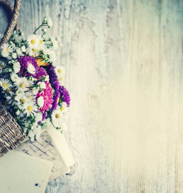 vintage kartı olan eski püskü ahşap masa üzerinde kalkık sepetteki renkli kır çiçekleri buketi