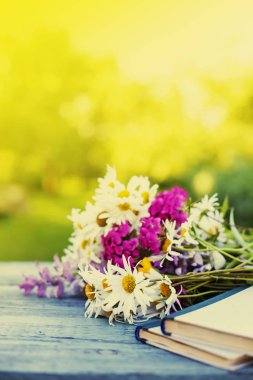 Kitaplar ile bahçe ahşap masa üzerinde renkli kır çiçekleri buketi