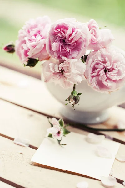 pink peony roses in vase with empty card outdoors