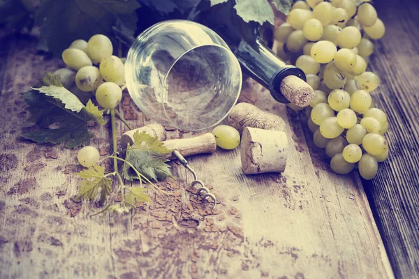 Bottle of white wine, grape and corks on wooden table