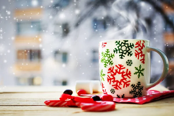 closeup view of coffee cup with marshmallows and christmas decorations over wooden table