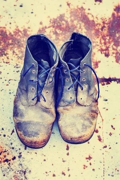 Old dirty vintage boots on rusty metal  surface