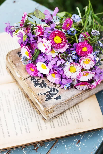 ぼろぼろの古い本にカラフルな野生の花の花束 — ストック写真