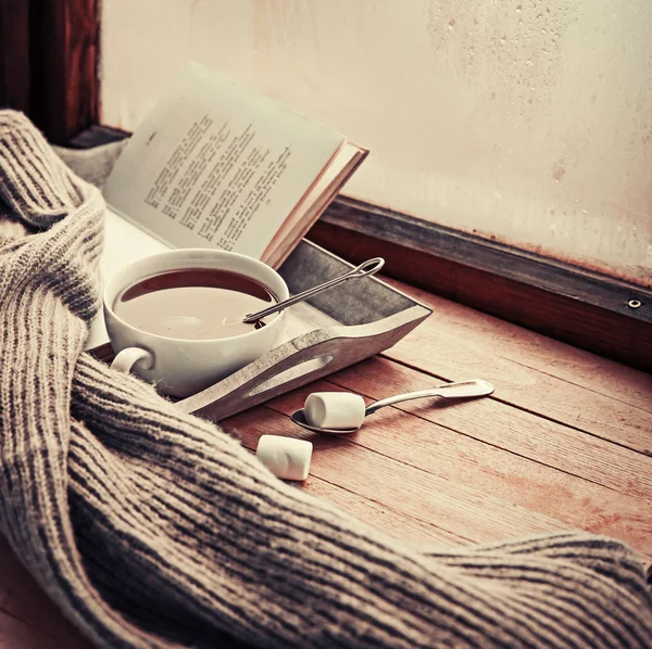 cup of hot tea and book on wooden surface